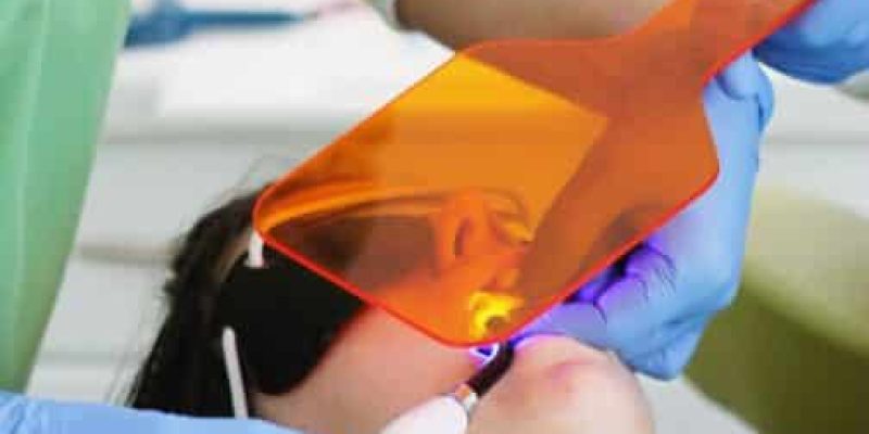 A dentist using a uv lamp to check the teeth of a woman